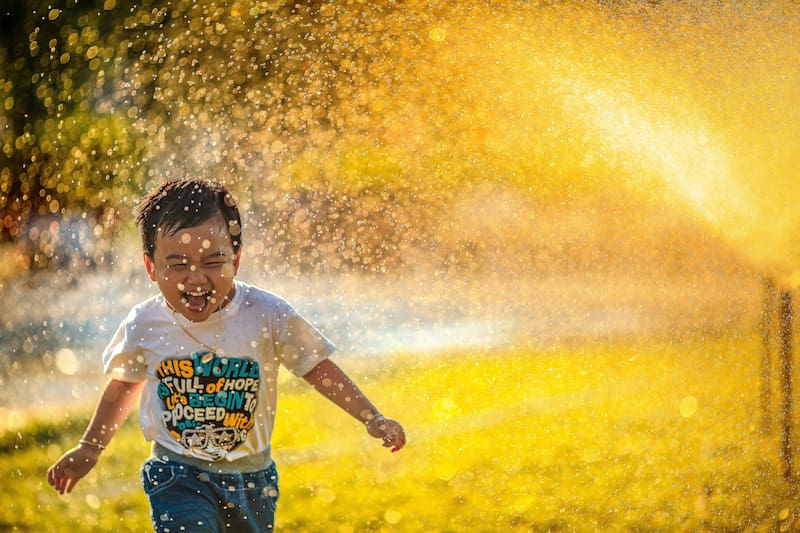 crianca brincando na agua sorrindo